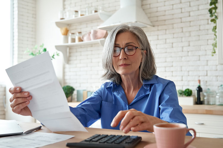 person holding paperwork about their entitlement to spouses pension on divorce using calculator