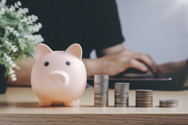 pink piggy bank with stacked coins on table