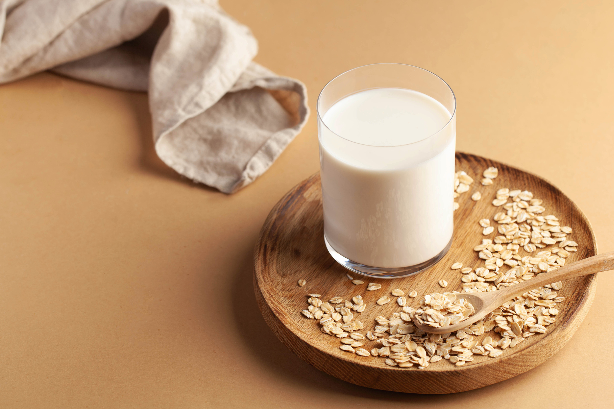 Oat milk in a glass surrounded by oats
