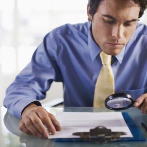 business man with a magnifying glass, reading the small print in a contract