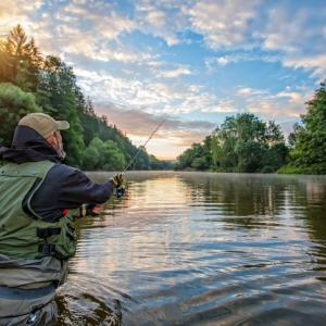 man wading into the river to fish, beautiful day. fishing rights concept.