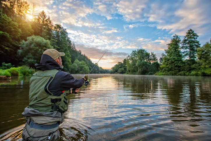 man wading into the river to fish, beautiful day. fishing rights concept.