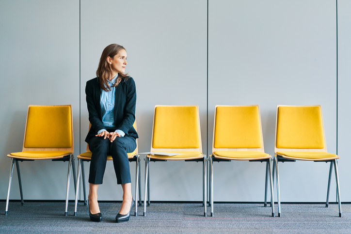 business omwan sitting on chair in line of empty chairs, waiting for an interview. concept for recruitment and retention challenges