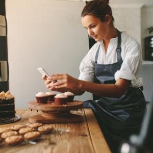 baker taking photograph of cakes on her phone for social media