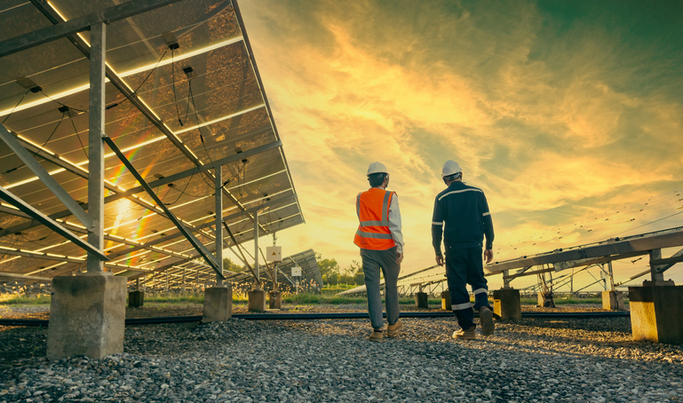 contractor walks investor through field of solar panels at sunset