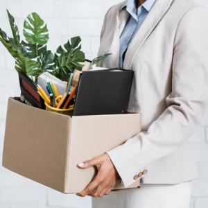 Close up of woman's hands holding a box of belongings from the office. Concept of employee leaving to join competitor, taking files with them.