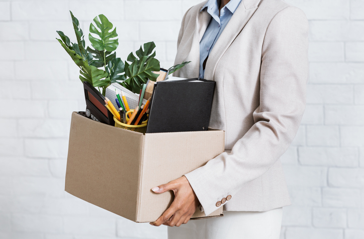 Close up of woman's hands holding a box of belongings from the office. Concept of employee leaving to join competitor, taking files with them.