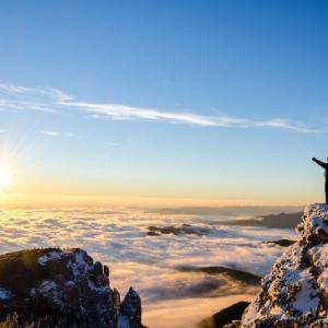 person silhouetted standing on the top of a mountain above the clouds, concept for new life after divorce