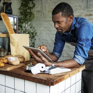 bread shop keeper looks at tablet, concept: researching commercial rent (coronavirus) bill