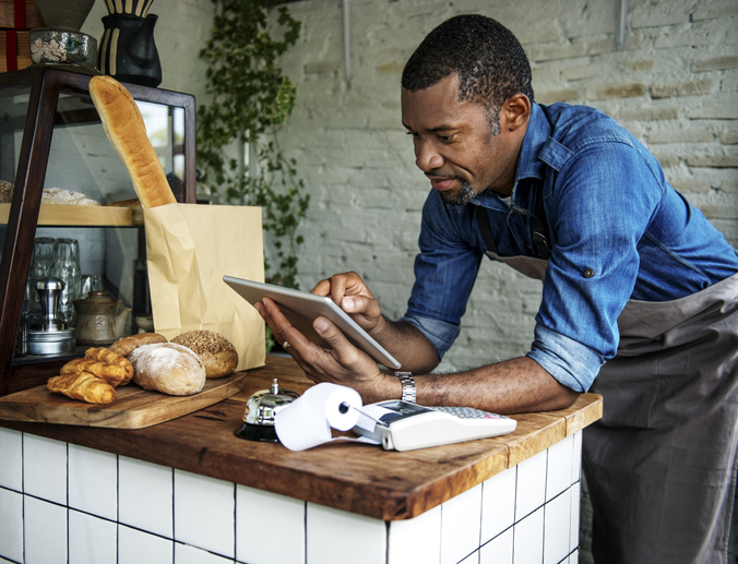 bread shop keeper looks at tablet, concept: researching commercial rent (coronavirus) bill