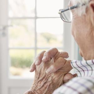 older man sits looking out of window