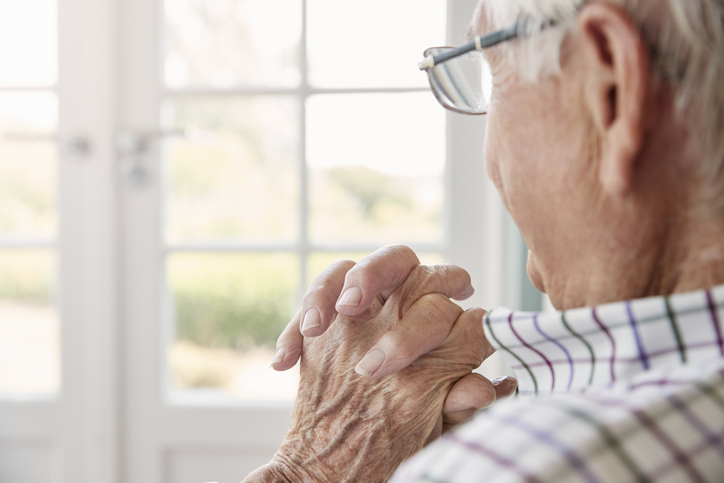 older man sits looking out of window