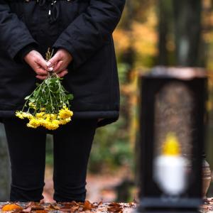 Woman holding flowers by a grave - concept for dealing with divorce after death