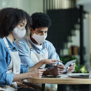 a couple wearing masks looking at laptop and finances, discussing protecting family business