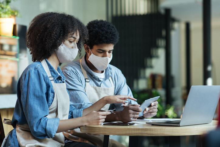 a couple wearing masks looking at laptop and finances, discussing protecting family business