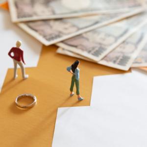 conceptual image with two figurines standing next to wedding ring and money. concept for pension sharing and pension in payment