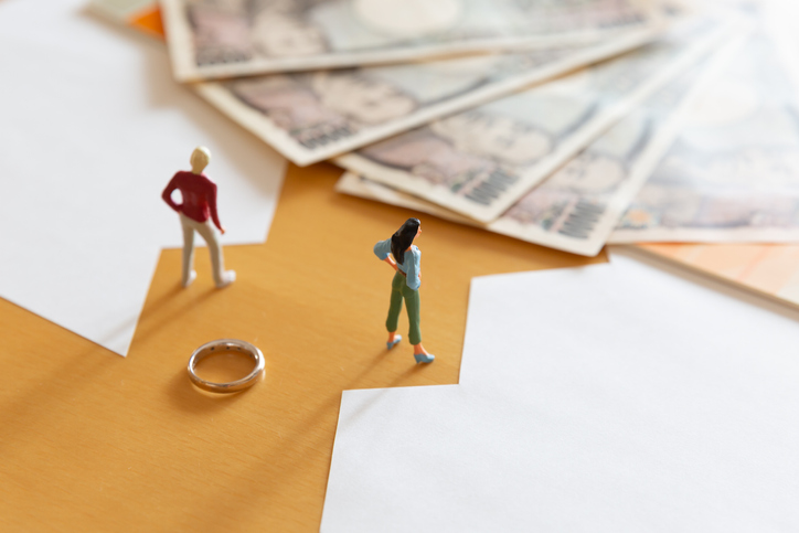 conceptual image with two figurines standing next to wedding ring and money. concept for pension sharing and pension in payment