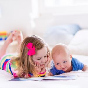 little girl with baby brother, reading a book. concept for blended families and children