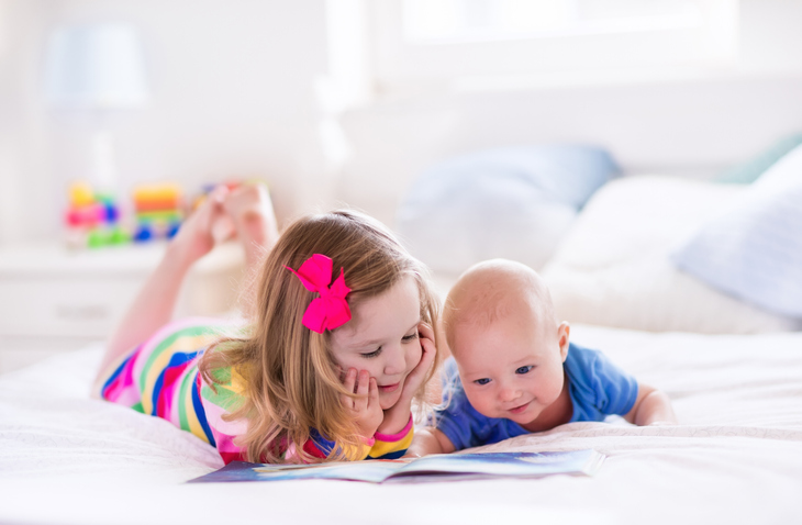 little girl with baby brother, reading a book. concept for blended families and children