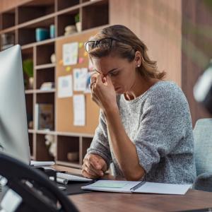 woman at desk pinching bridge of nose in stress over disputes