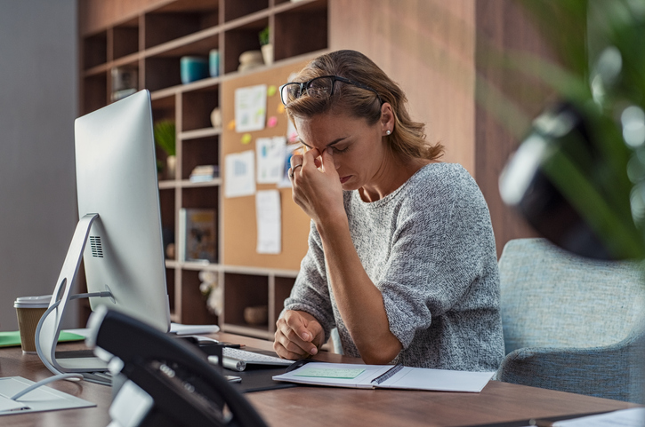 woman at desk pinching bridge of nose in stress over disputes