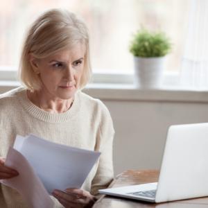 older woman at laptop, going through pensions, working out overseas pensions