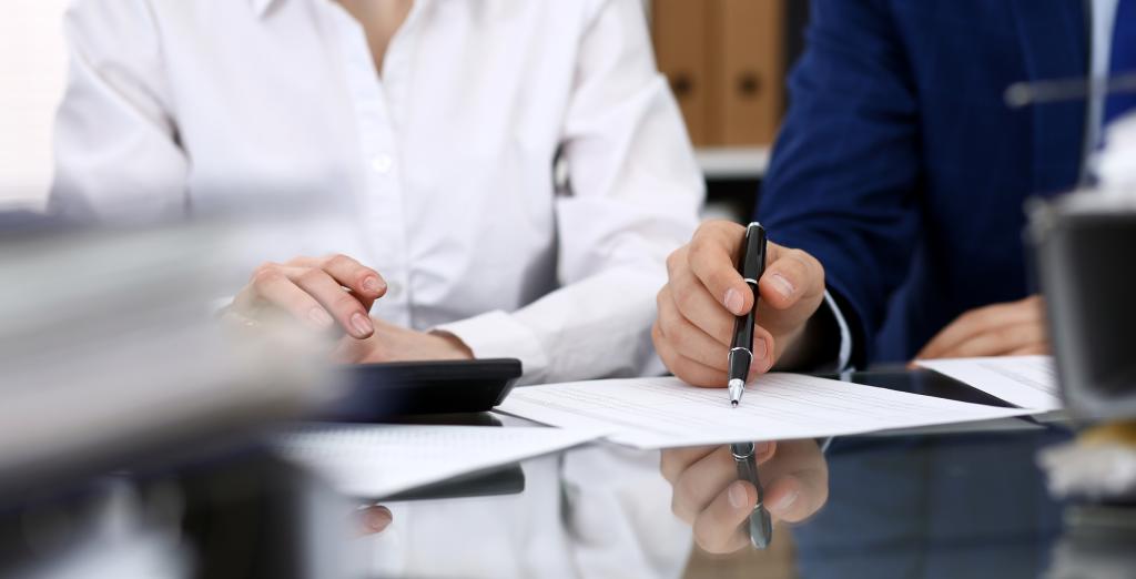 Calculations being made by two work colleagues using a calculator and documents