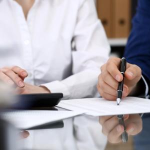 Calculations being made by two work colleagues using a calculator and documents