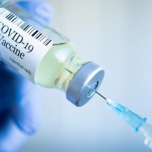 bottle of covid-19 vaccination with needle being inserted into it. concept image for mandatory vaccinations