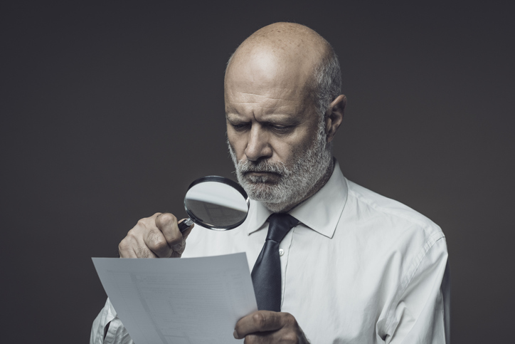 business man with magnifying glass, looking at contract. concept image for reading a restrictive covenant in contract