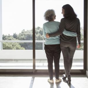 happy elderly mother and adult daughter looking out of window. concept for bank of mum and dad