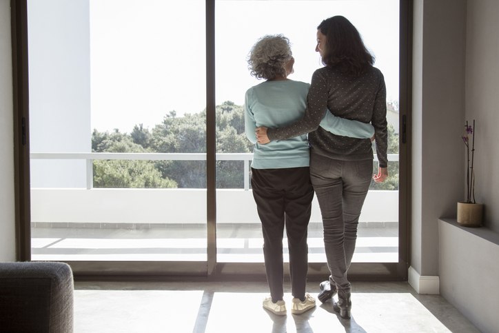 happy elderly mother and adult daughter looking out of window. concept for bank of mum and dad