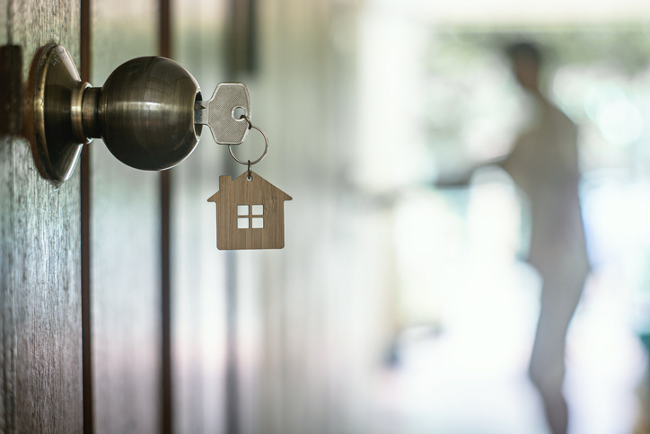 key with metal house ornament hanging from open door