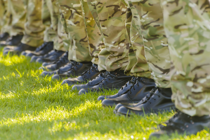 line of feet wearing military boots and camo trousers. concept for armed forces pension