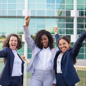 three happy business women at work celebrating achievement