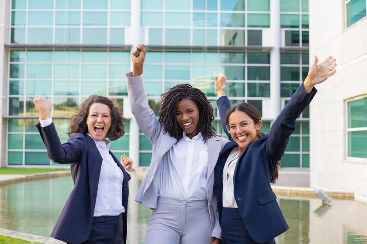 three happy business women at work celebrating achievement