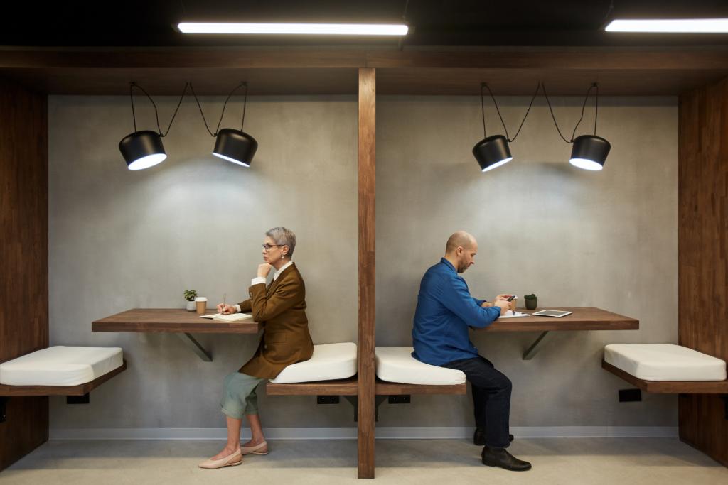 Two adults sit facing away from each other in a cafe booth to showcase Pension division in divorce