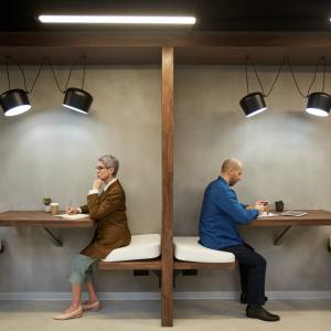 Two adults sit facing away from each other in a cafe booth to showcase Pension division in divorce
