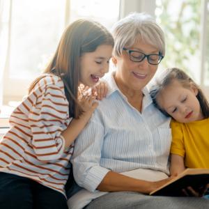 two children reading with grandma. concept for babysitters and sleepovers with family