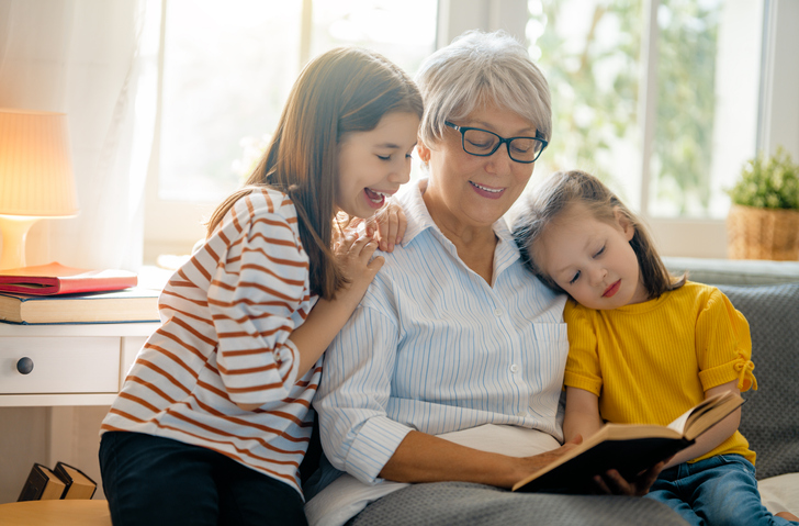 two children reading with their grandmother.