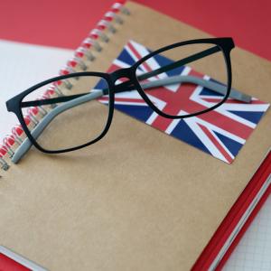 glasses on top of a notebook with a british flag on it. concept for applying for UK work visas