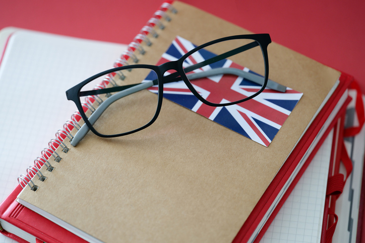glasses on top of a notebook with a british flag on it. concept for applying for UK work visas
