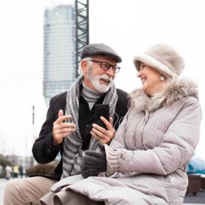 senior couple listening to music together on phone, smiling. concept for falling in love in later life