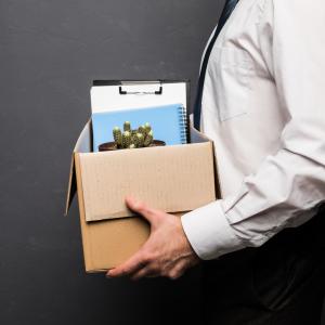 Man carrying cardboard box containing his work items following employee dismissal