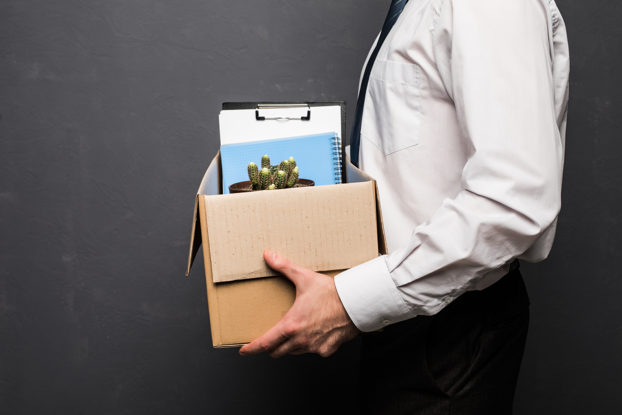 Man carrying cardboard box containing his work items following employee dismissal