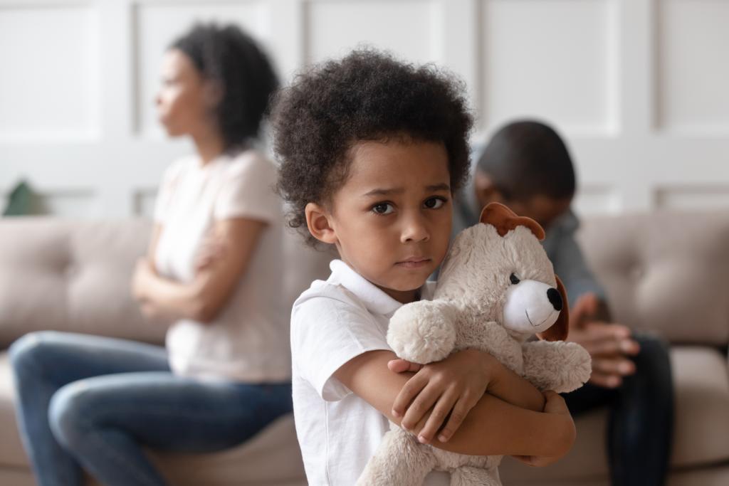 Upset little child boy holding toy looking at camera