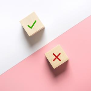 photo of two wooden blocks, one with a checkmark and the other a cross