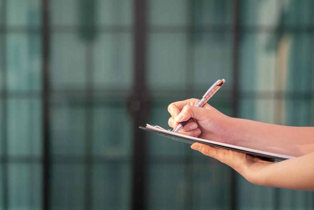 person holding a notebook and writing