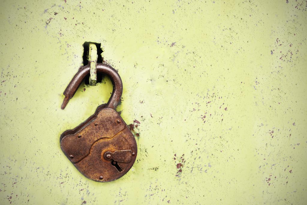 Old rusty lock without a key on a yellow background
