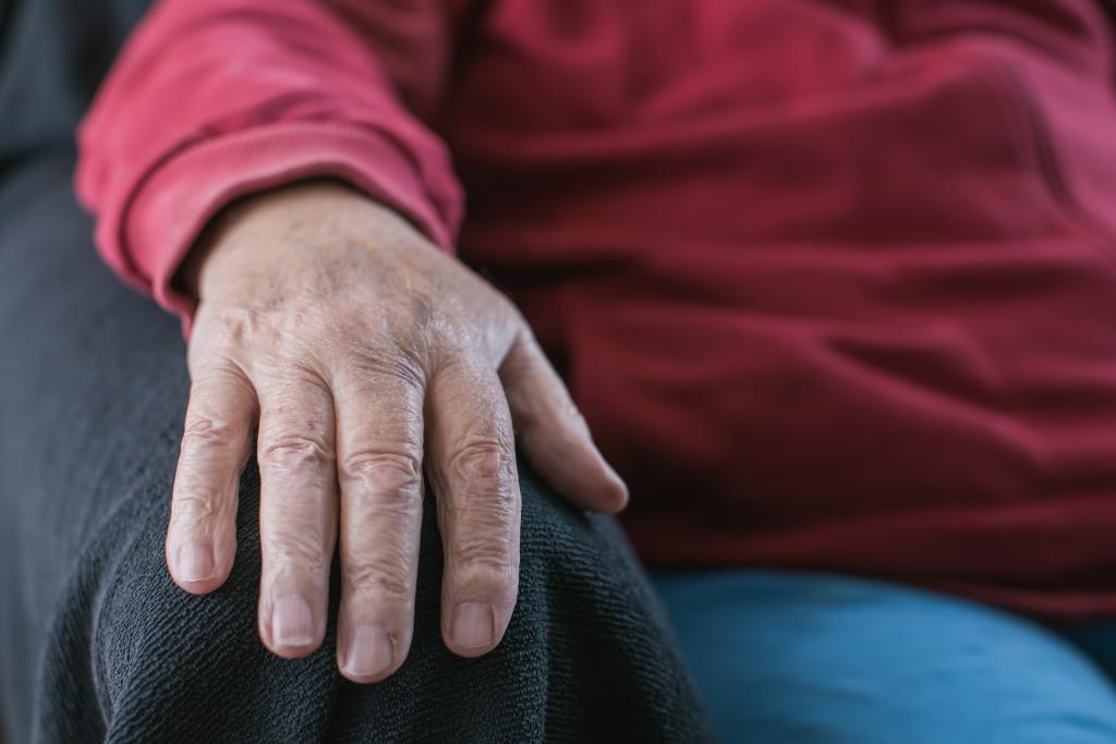 old person's hand resting on armchair